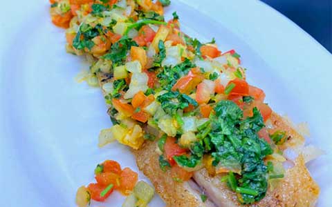 Corvina - Fresh filet of corvina prepared the Caribbean way on a hot grill with lots of onions, fresh tomatoes and cilantro